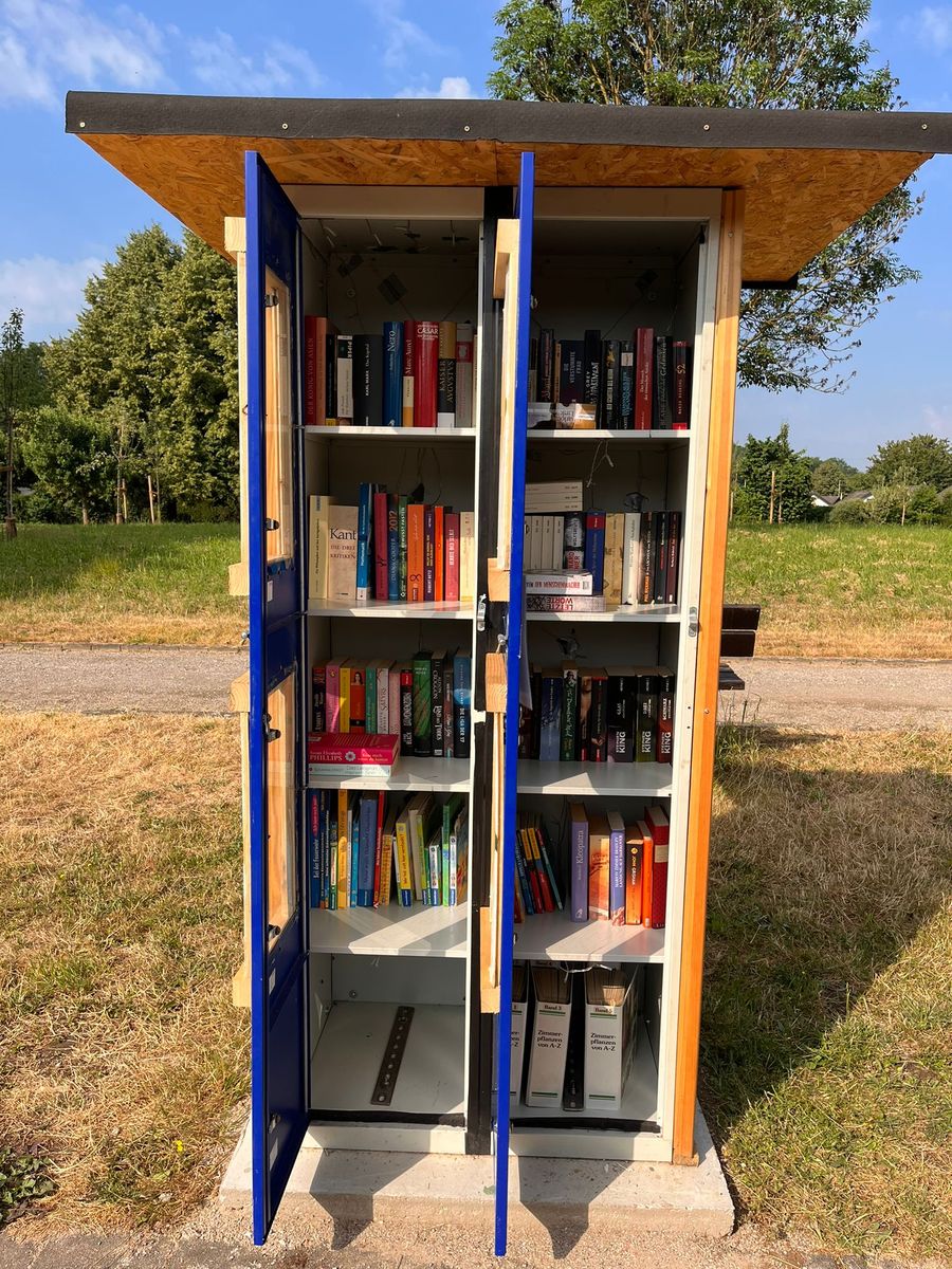 Der neue offene Bücherschrank aus Holz mit blauen Glastüren, gefüllt mit Büchern
